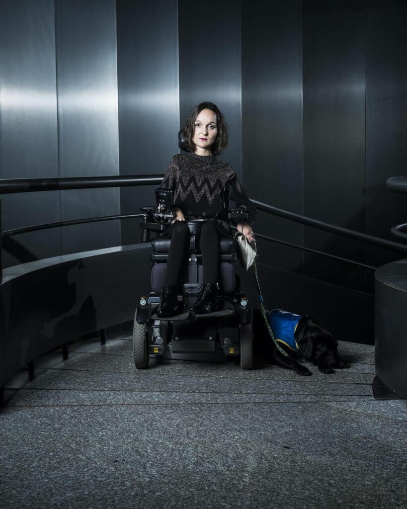 Photo de Charlotte, habillée en noir, dans une cage d'escalier noir. Ambiance Dark Vador.