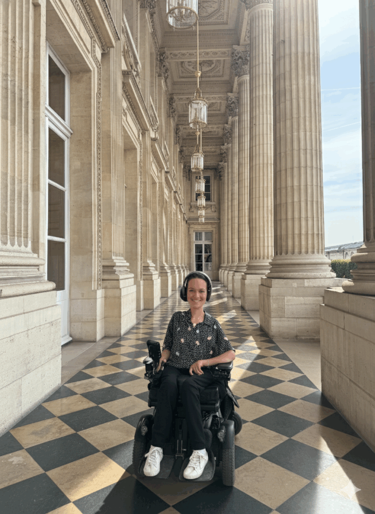 photo de Charlotte sur la terrasse de l'hôtel de la Marine avec un audioguide sur les oreilles