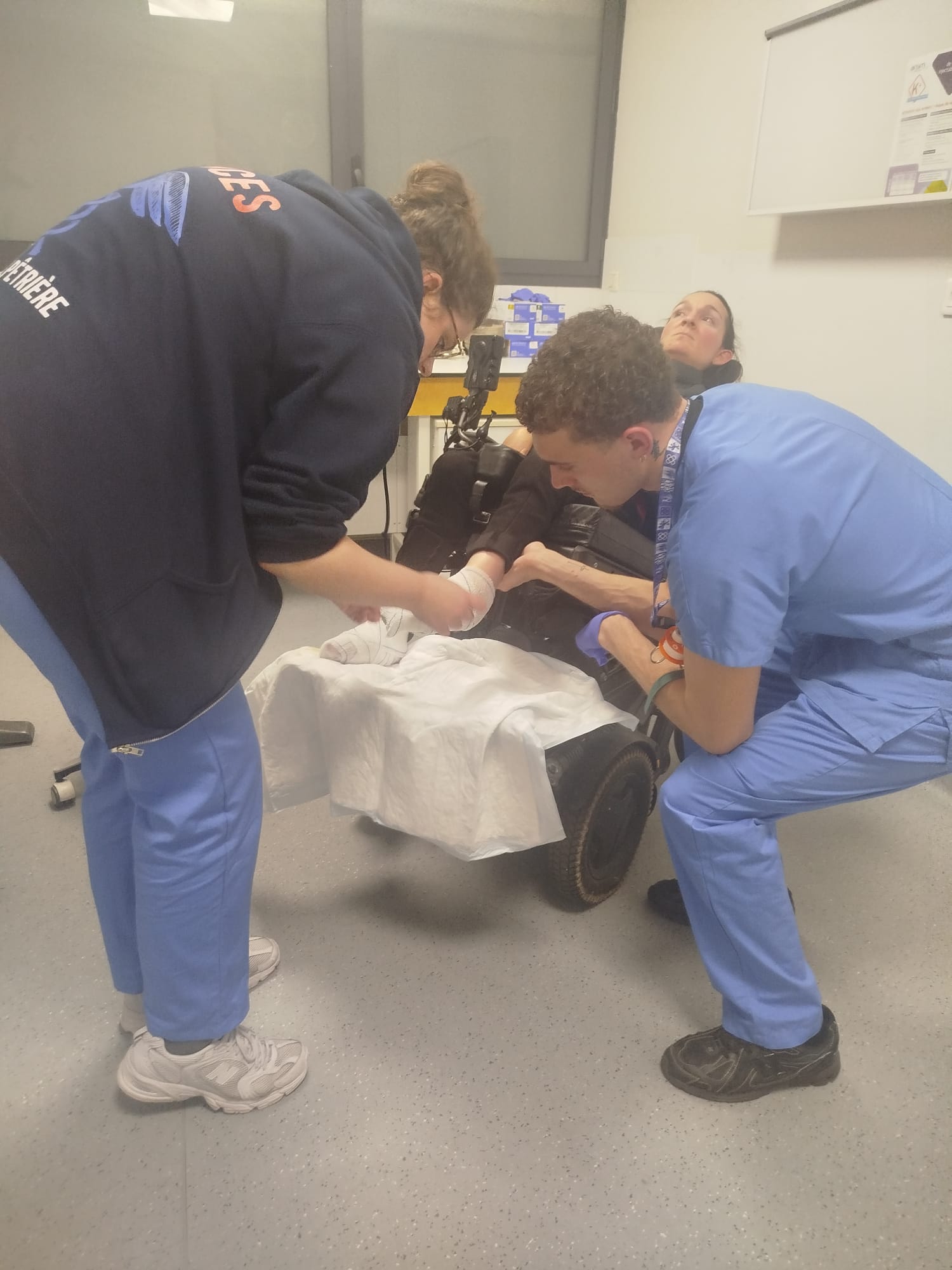 Photo de Charlotte aux urgences avec des infirmiers en train de lui faire des bandages aux pieds